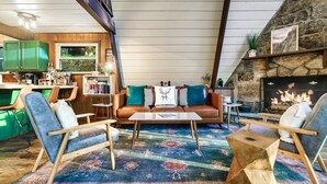 A cozy living room with a brown leather sofa, blue chairs, and a patterned rug.