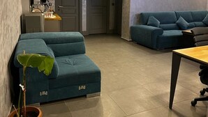 A modern living room with a teal sofa, a coffee table, and two potted plants. - Dilens Bosphorus Hotel (Istanbul)