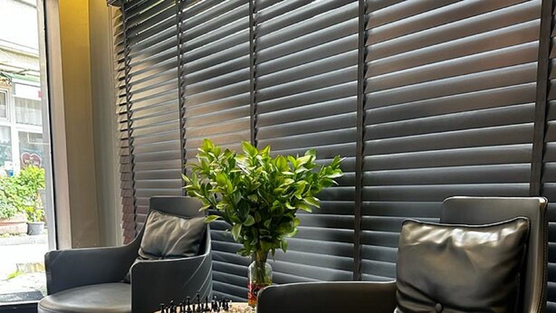 A modern lounge area with two black leather chairs, a small round table with a chess set, and a potted plant. - Dilens Bosphorus Hotel (Istanbul)