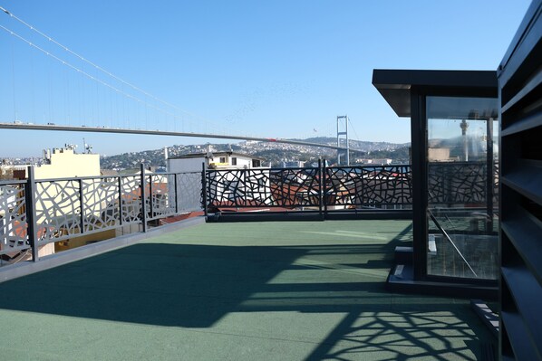 Terraza en la azotea con vistas a un puente y al paisaje urbano.