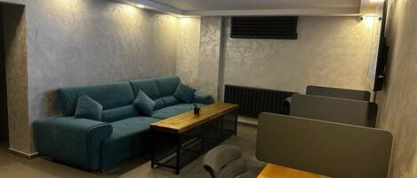 Habitació moderna amb un sofà color turquesa, una taula de fusta i una separació negra.