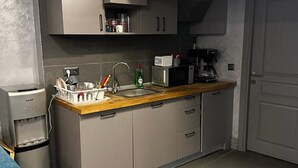 A compact kitchen with grey cabinets, a stainless steel sink, and a coffee machine. - Dilens Bosphorus Hotel (Istanbul)