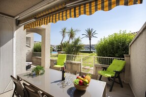 Un balcon avec une table, des chaises et un saladier rempli de fruits.