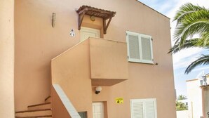 Ein Gebäude mit einer geschwungenen Fassade, einer Steintreppe und einem kleinen Balkon mit Fensterläden.