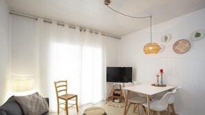 Ein modernes Wohnzimmer mit einer Couch, einem Esstisch mit Stühlen, einem Fernseher und Wanddekoration.