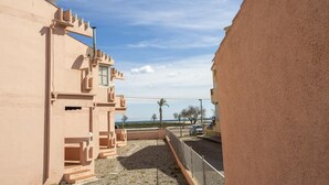 Ein Gebäude mit einer beigen Fassade, einem Balkon mit Metallgeländer und einem wolkenlosen Himmel.