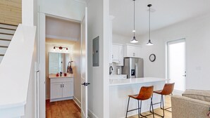 Eine moderne Küche mit weißen Schränken, einem Edelstahlkühlschrank und einer Bar mit zwei Hockern.