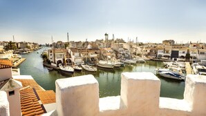 Un port où des bateaux sont amarrés, un ciel dégagé et des bâtiments en arrière-plan.