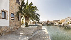 Une propriété située au bord de l’eau, dotée de murs en pierre, d’une terrasse en bois et d’un port de plaisance avec des bateaux.