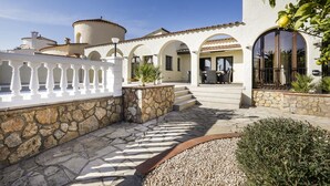 Ein Gebäude im mediterranen Stil mit Steinmauern, Bogenportalen und einem Innenhof mit weißer Brüstung.