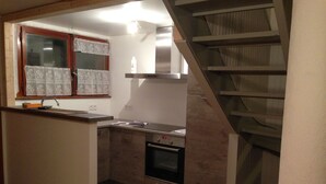 A compact kitchen with a built-in oven, a small countertop, and a window with curtains. - La Clusaz in a quiet location 300m from the village center (La Clusaz)