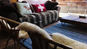 A cozy living room with a sofa, a chair, and a wooden table. - La Clusaz in a quiet location 300m from the village center (La Clusaz)