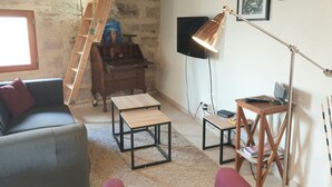 Ett mysigt vardagsrum med en trästege, en tv som är monterad på väggen, ett skrivbord med en lampa och en soffa.