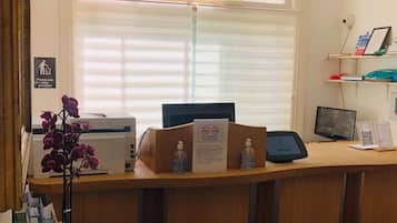 A reception desk with a computer, printer, and a sign indicating no smoking.