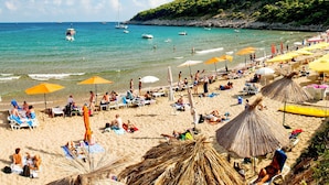 Una playa con tumbonas, sombrillas y gente relajándose.