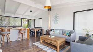 A modern living space with a dining area, a sofa, and a coffee table. - Waterfront Pet-Friendly Home - Oceanview Cottage (Malua Bay)
