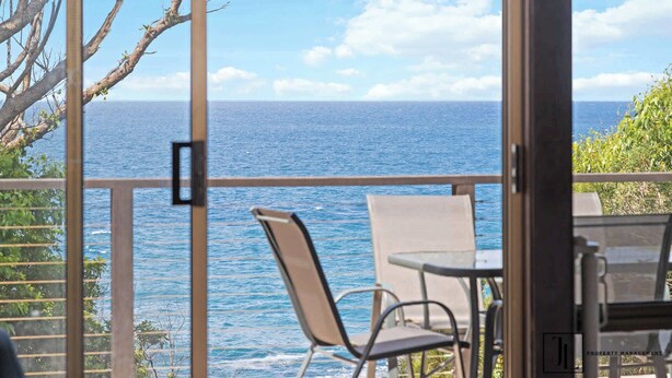 A balcony with a view of the ocean, a chair, and a table. - Waterfront Pet-Friendly Home - Oceanview Cottage (Malua Bay)