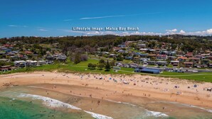 A beach with houses in the background. - Waterfront Pet-Friendly Home - Oceanview Cottage (Malua Bay)