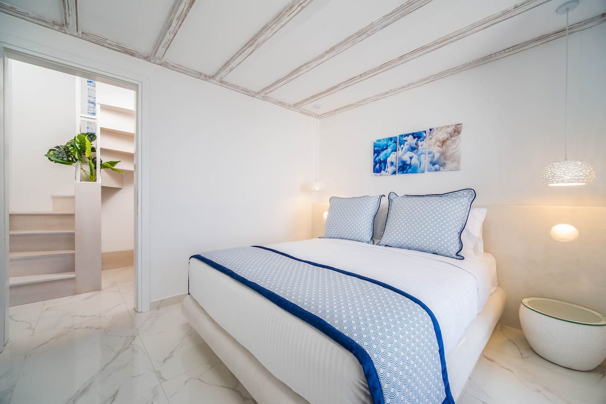 Ein Schlafzimmer mit Bett, Treppe und Wandleuchte.