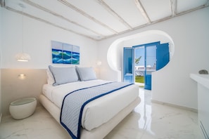 A modern bedroom with a bed, a round mirror, and a view of the outside. - Kyklos luxury Villas with private pool (Santorini)