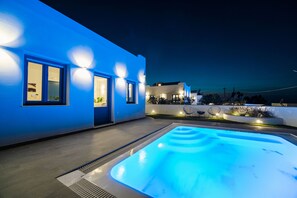Um edifício moderno com piscina, janelas iluminadas e área de estar ao ar livre.