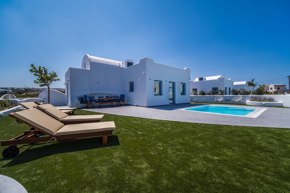 Eine moderne, weiße Villa mit Pool, Sitzgelegenheiten im Freien und einem gepflegten Rasen.