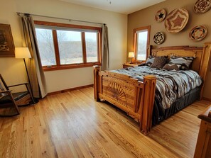 A bedroom with a wooden bed, a large window, and a mirror on the wall. - Casa La Capilla: Rural Creekside Retreat near SF (Santa Fe)