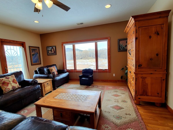 A spacious living room with a leather sofa, a wooden coffee table, and a large cabinet.