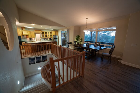 A spacious kitchen with wooden cabinets, a dining area with a wooden table and chairs, and a staircase with a wooden railing.