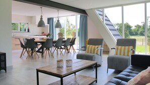 Una sala de estar moderna con comedor, ventanas amplias y vistas al exterior.