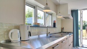Una cocina moderna con encimeras de acero inoxidable, horno empotrado y un amplio ventanal.
