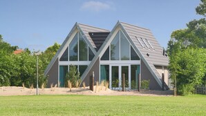 Una casa moderna con techo triangular y ventanas amplias.