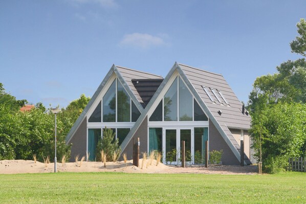A modern house with a triangular roof and large windows.
