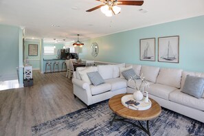 A spacious living room with a white sofa, a wooden coffee table, and a blue patterned rug.