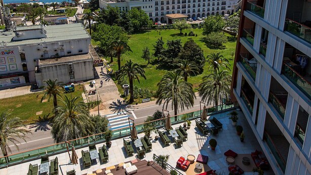 A rooftop pool area with lounge chairs and a view of the sea. - Hotel Plaza (Budva)