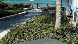 A pathway leading to a building with a view of the ocean and palm trees. - Exuma Oceanfront-Steps to the beach-Side Quest (George Town Exuma)