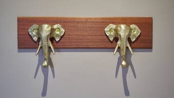 Deux crochets muraux en métal, en forme d’éléphant, fixés sur un panneau en bois.