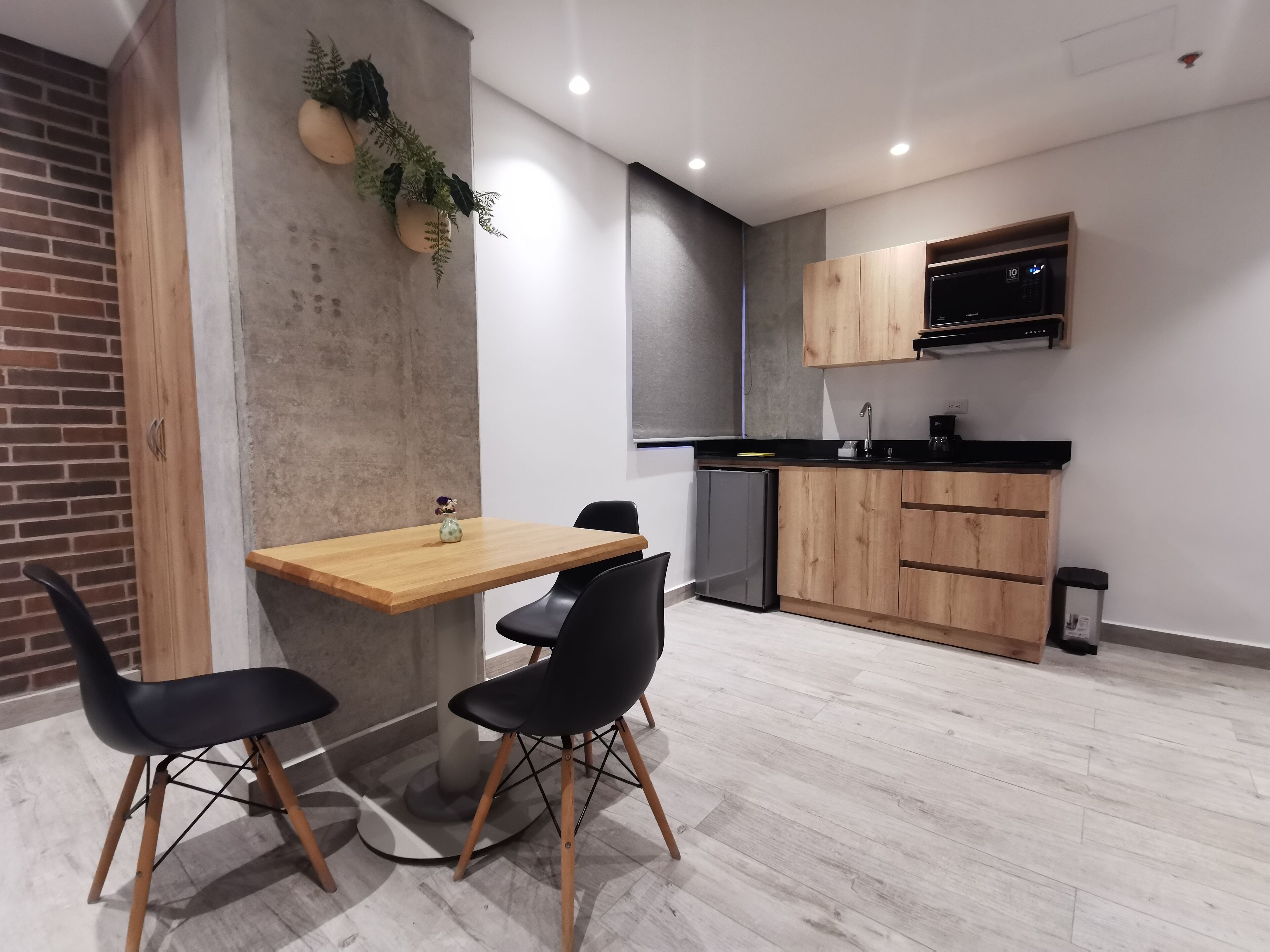 A modern kitchen with wooden cabinets, a black countertop, and a built-in microwave.