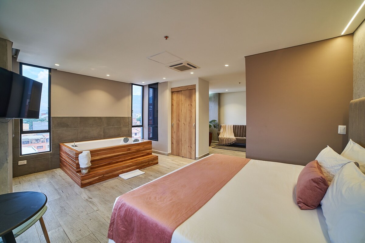 A modern bedroom with a large bed, a wooden bathtub, and a view of the city.