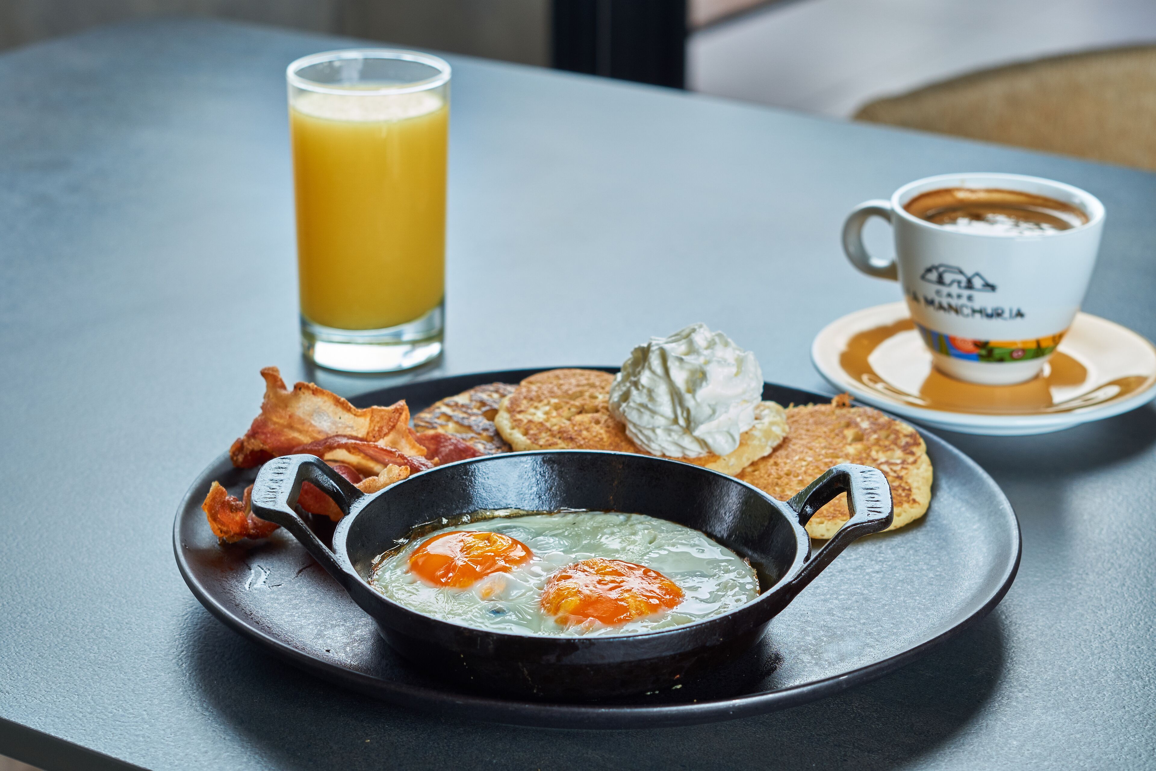 Un plato de desayuno con huevos, tocino, tostadas y una taza de café sobre una mesa.