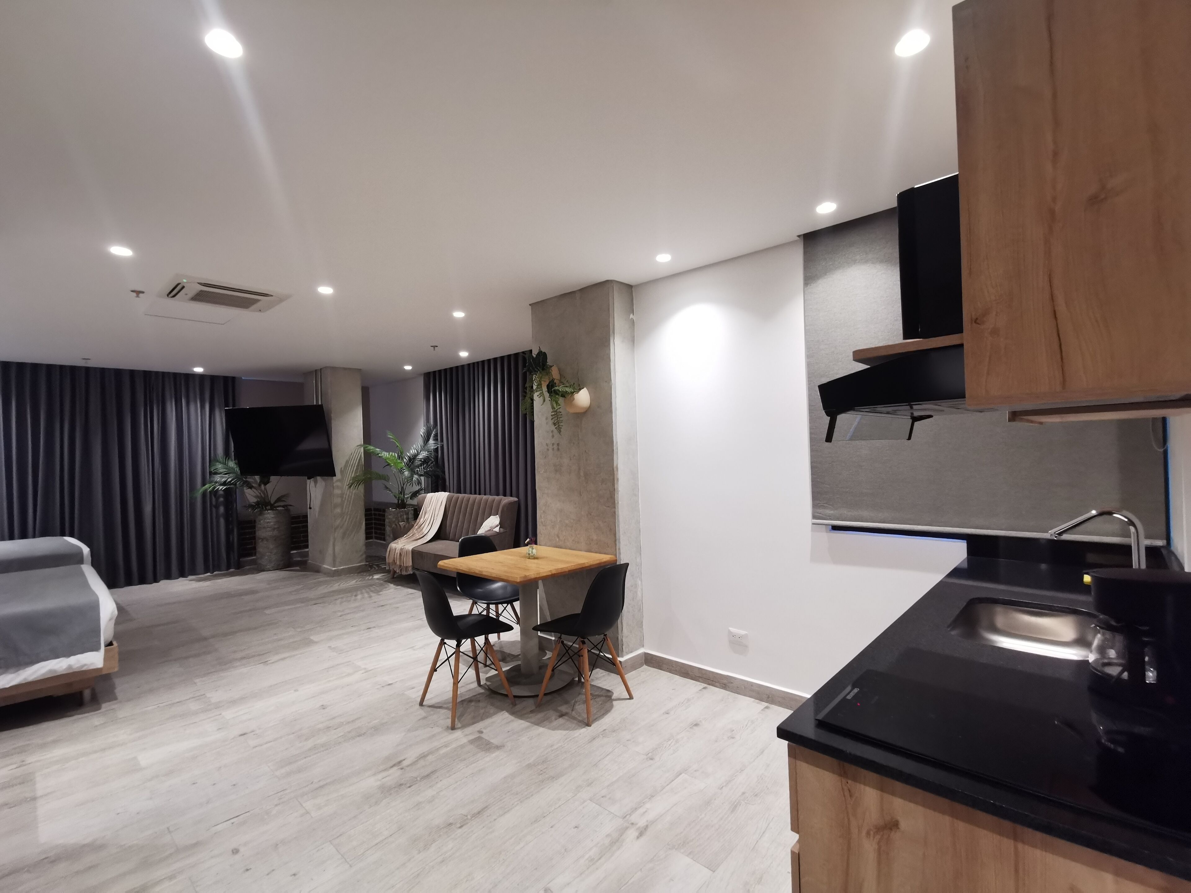 Una cocina moderna con encimera negra y armarios de madera. Hay una zona de comedor con una mesa y sillas.