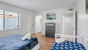 A bedroom with two beds, a desk, a chair, and a painting on the wall. - Beautiful 1bd, prime location, free parking, bbq, pets (Delray Beach)