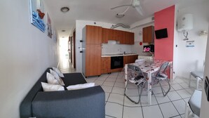 A compact living space with a sofa, dining table, and kitchen area.