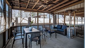 Eine Terrasse im Freien mit Holzboden, einem Tisch mit Stühlen, einer Sitzecke und einem Mülleimer.
