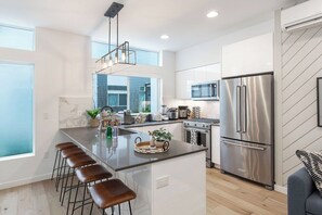 Una cocina moderna con una isla central, electrodomésticos de acero inoxidable y vistas al exterior.