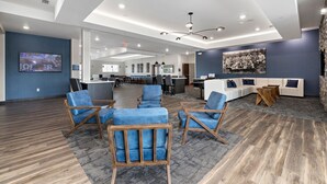 A modern office space with a large TV screen, comfortable seating, and a mix of wooden and carpeted flooring. - Holiday Inn Express Kansas City North – Parkville by IHG (Parkville)