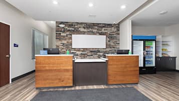 A reception area with a stone wall, two wooden counters, a whiteboard, and a refrigerator stocked with beverages.