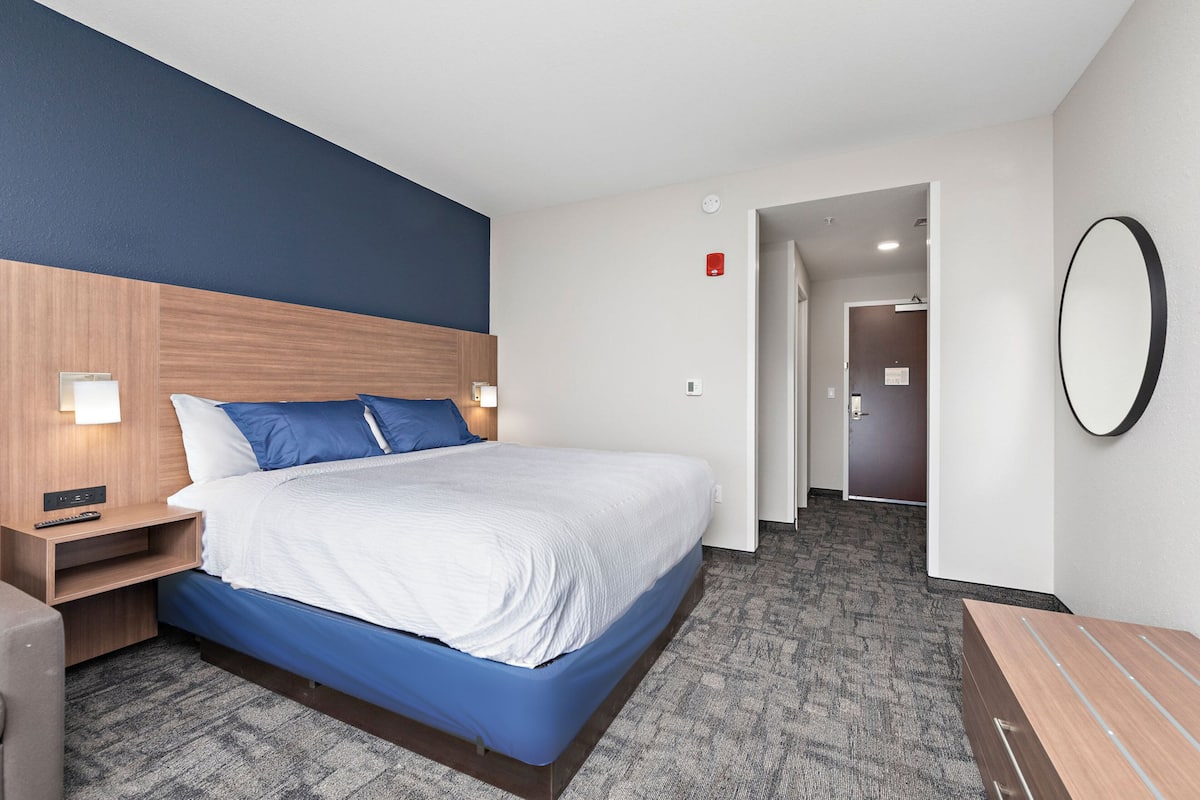 A hotel room with a bed, nightstands, a desk, and a mirror.