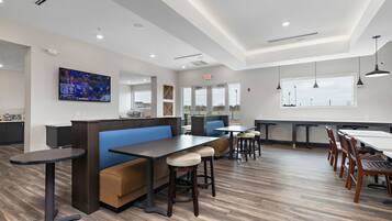 Un restaurante moderno con mesas altas, cabinas y taburetes de bar.