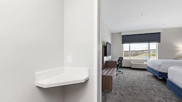 Een hotelkamer met een bed, een bureau met stoel, een televisie en een raam met uitzicht.